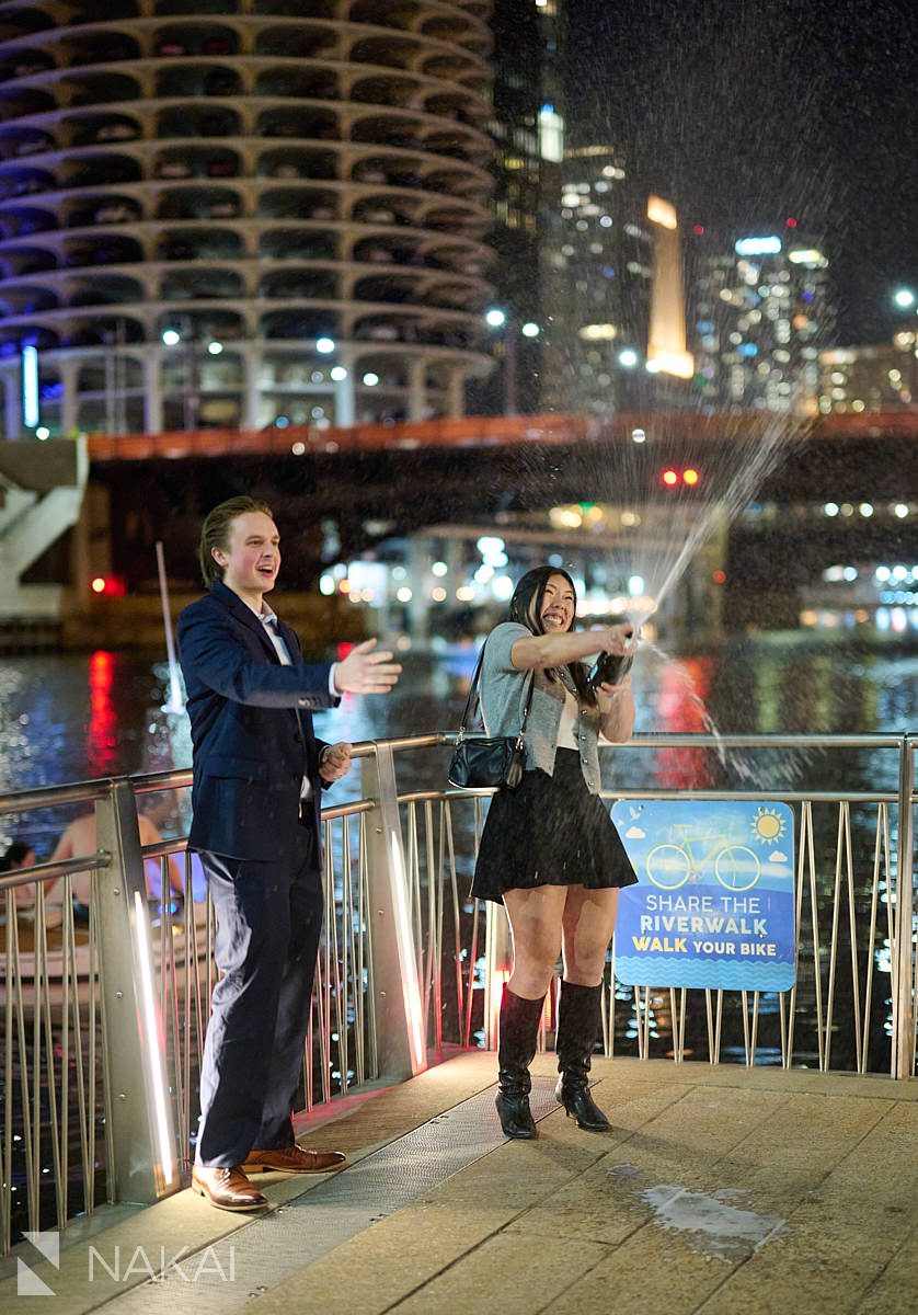 surprise proposal chicago pictures spraying champagne on riverwalk at night.