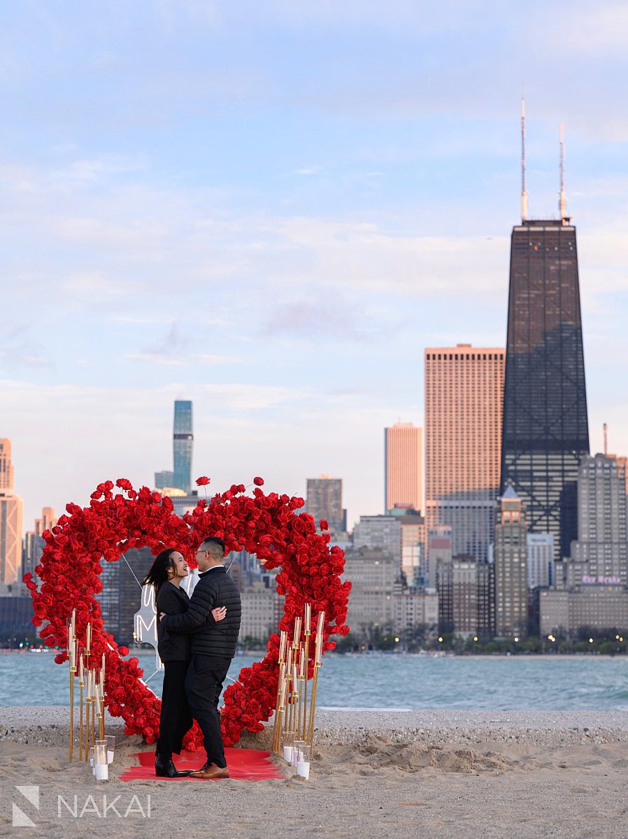 rose heart wreath backdrop on North Ave Beach. Engagement proposal ideas Chicago with skyline 