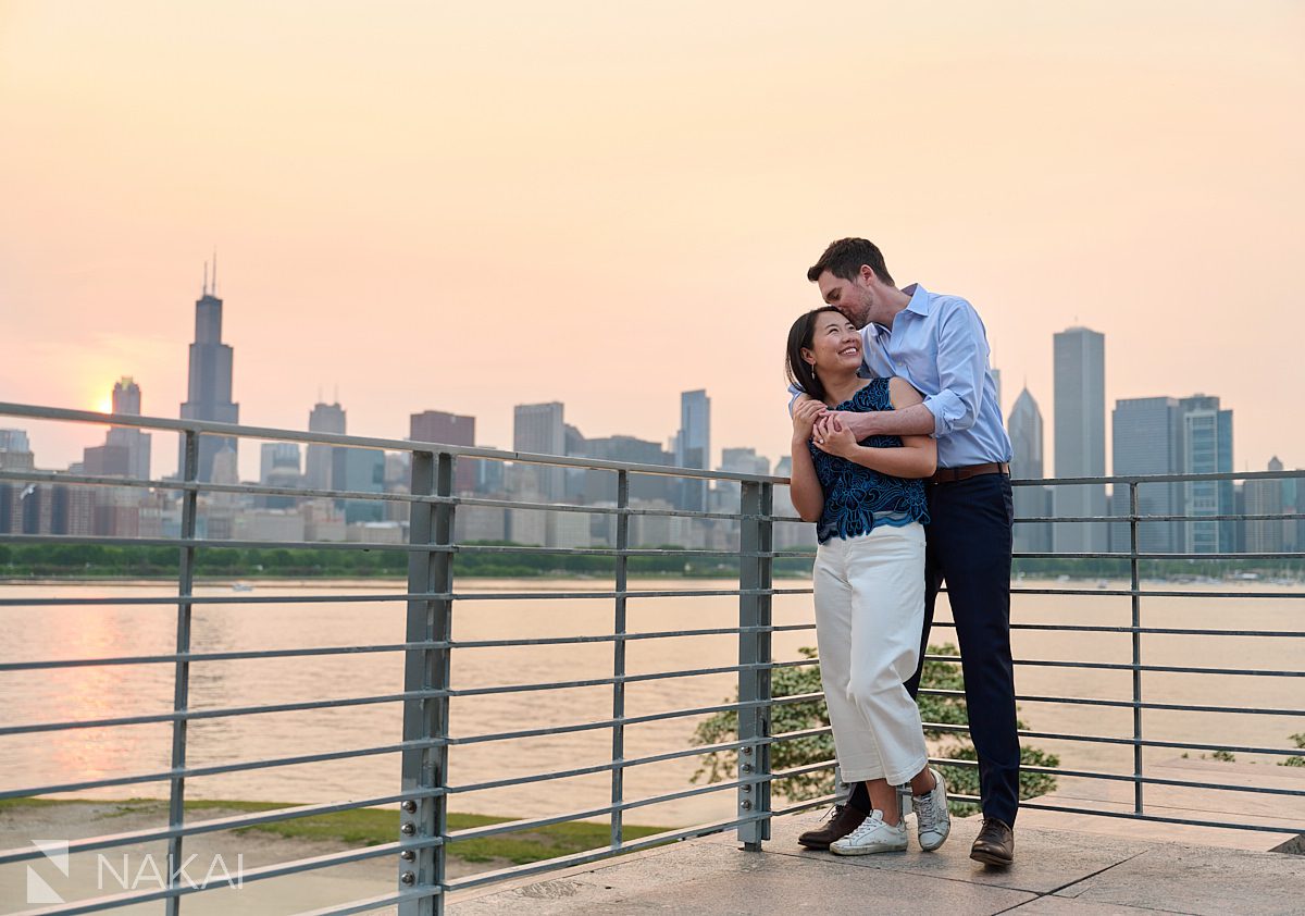 museum campus engagement skyline photos setting sun orange haze sky kissing on the cheek