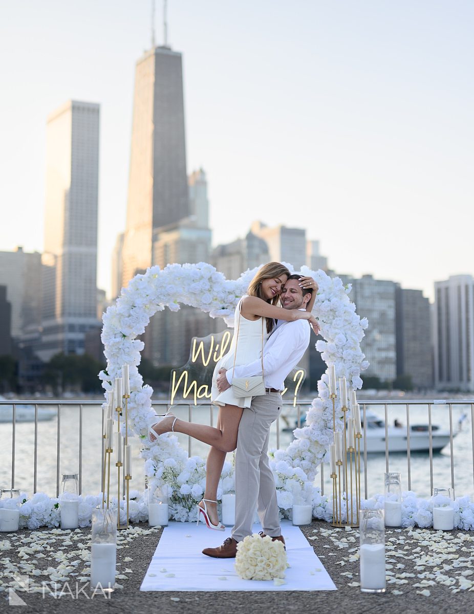 chicago proposal spots sunset at Olive Park lift and hug with white roses arch