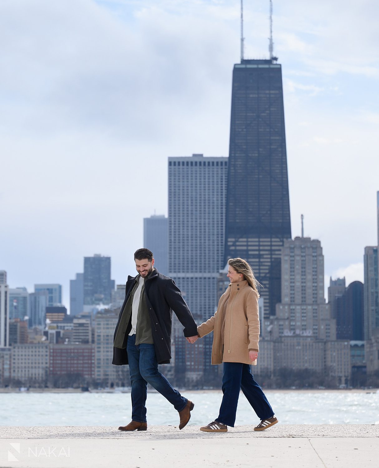 engagement picture, couple walking at North Ave Beach with skyline in background
