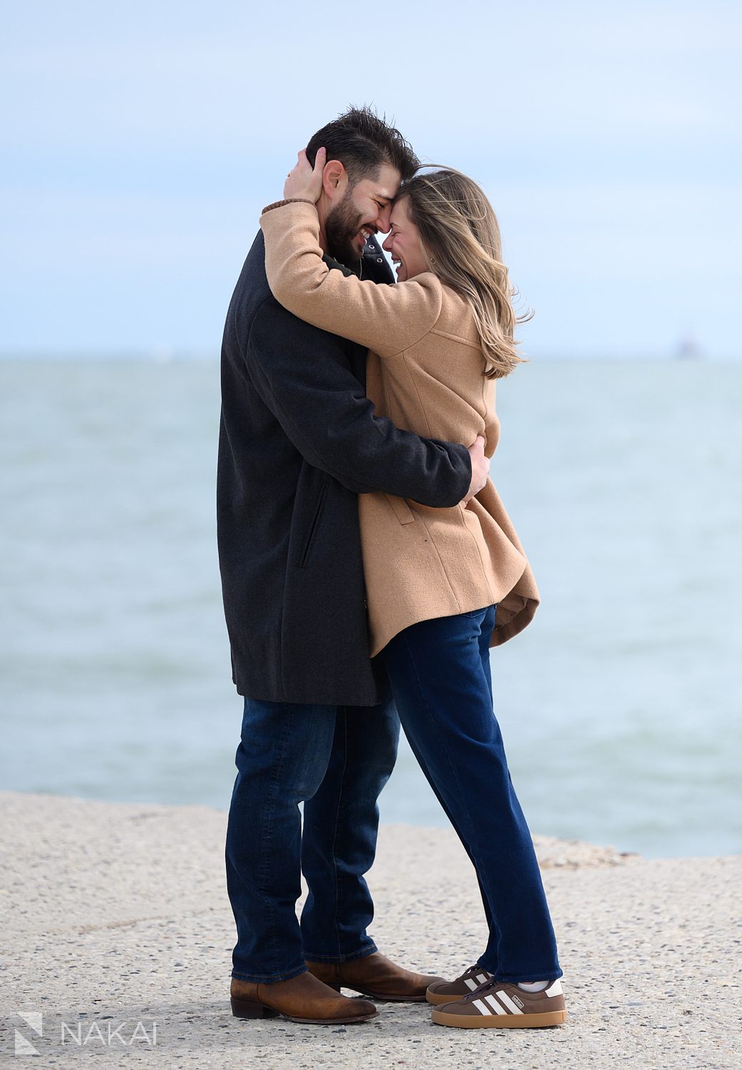newly engaged couple standing, foreheads touching at North Ave beach