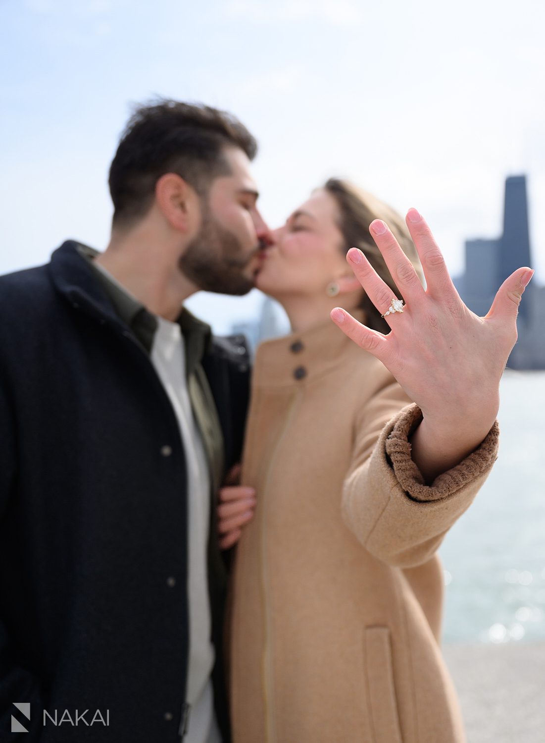 newly engaged couple kissing holding out hand with her ring on it during their North Ave beach proposal