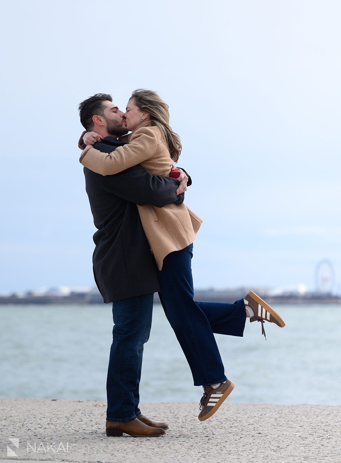 newly engaged couple kiss and lifting her off her feet after their North Ave beach proposal