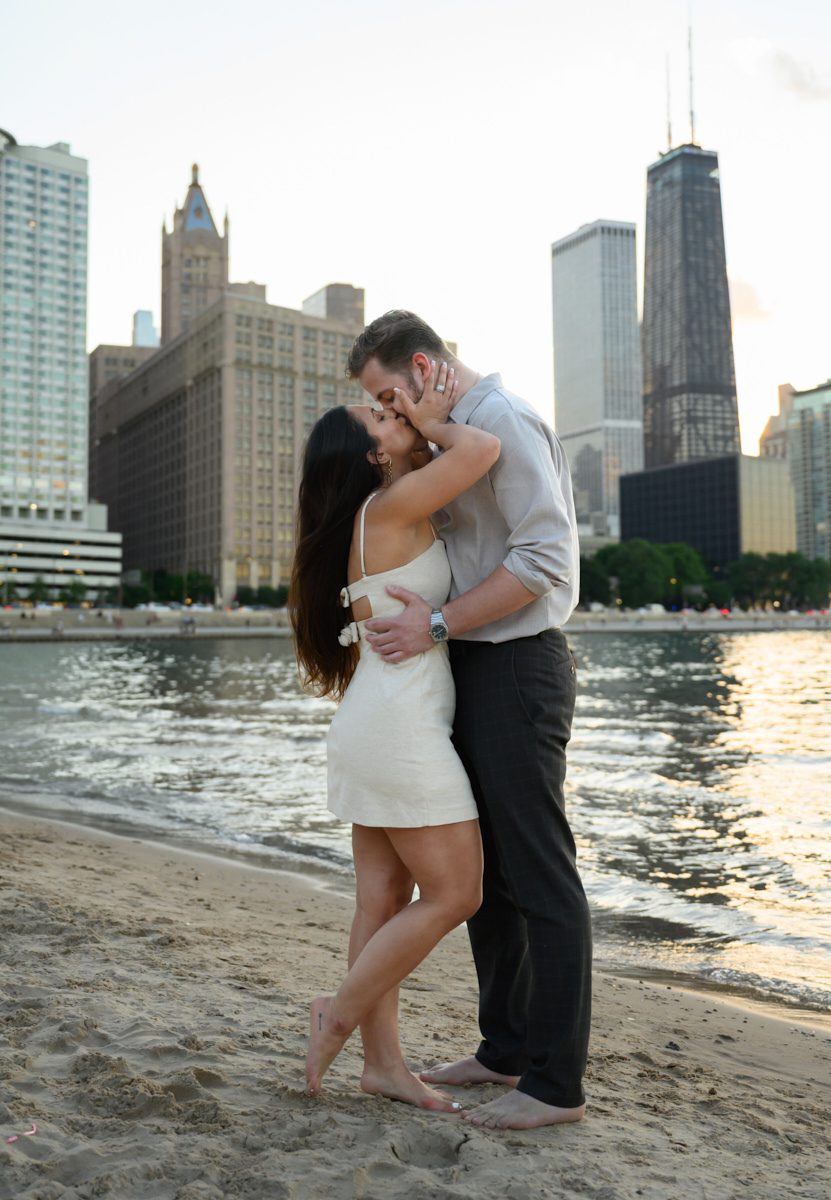 kiss in sand at Chicago oak st beach engagement