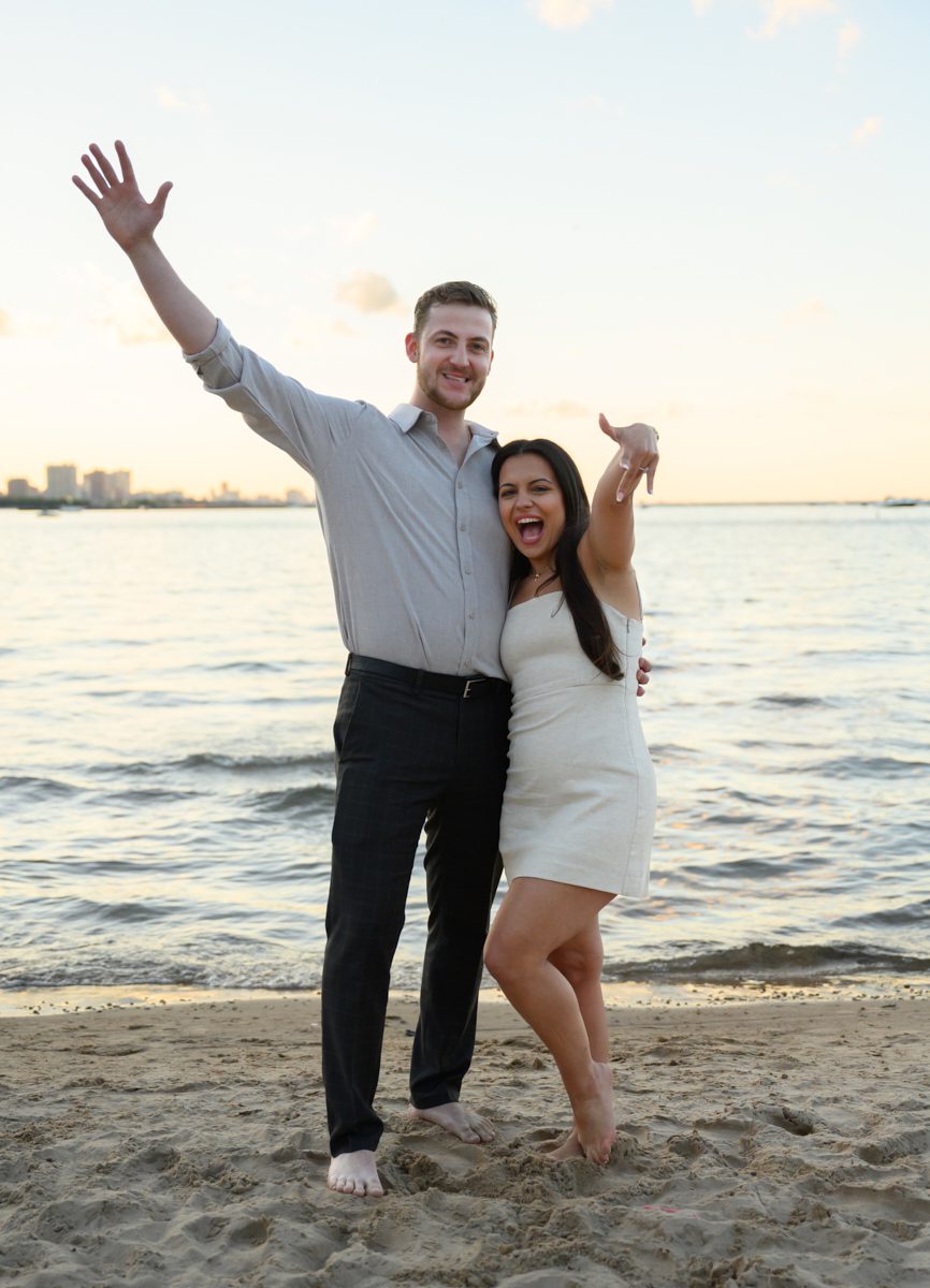 photo of couple showing off ring in sand at Chicago oak st beach engagement