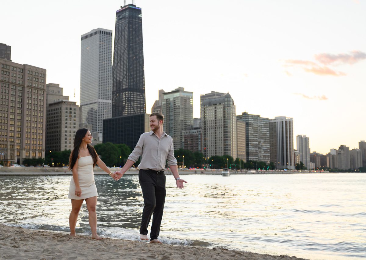 walking with skyline in background at Chicago oak st beach engagement