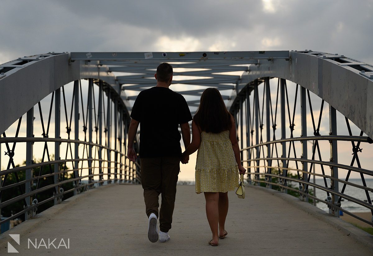 couple walking on bridge at sunrise during chicago lakefront engagement