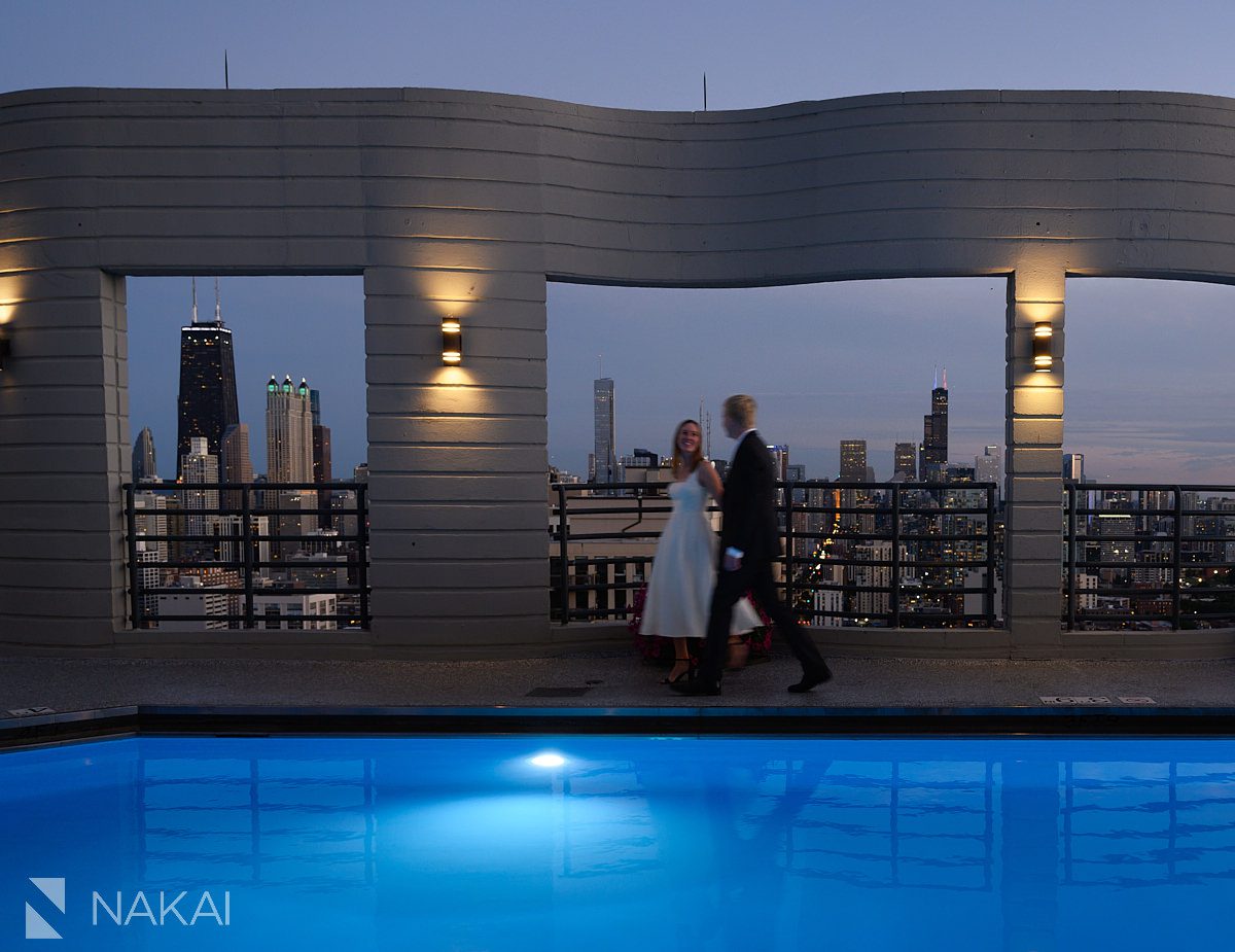 sunset chicago rooftop engagement photos skyline in background couple walking, motion blur pool in foreground