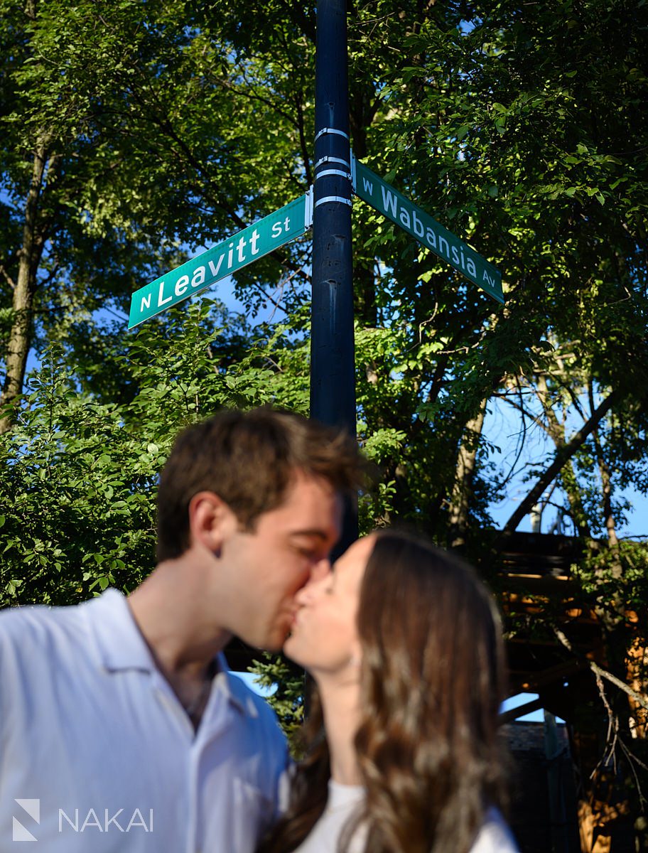 chicago neighborhood engagement picture, close up of couple kissing with street signs above them in Wicker Park